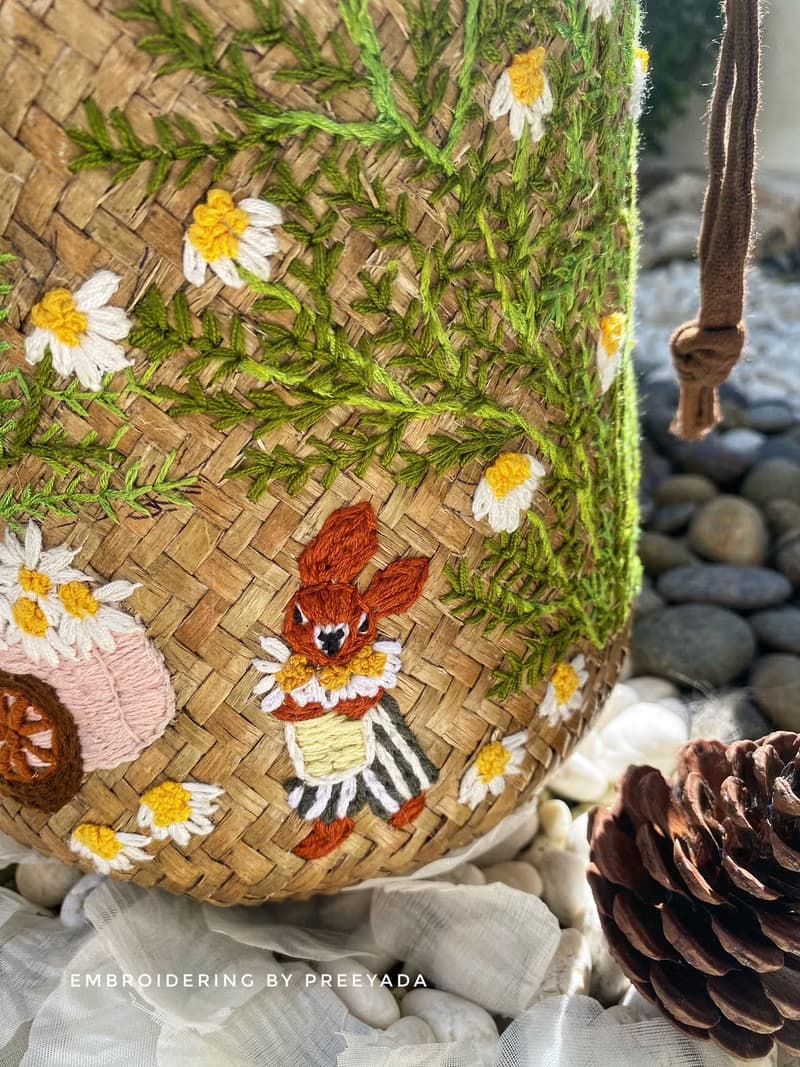 Thai woven rattan bag with hand-embroidered daisy and rabbit pattern