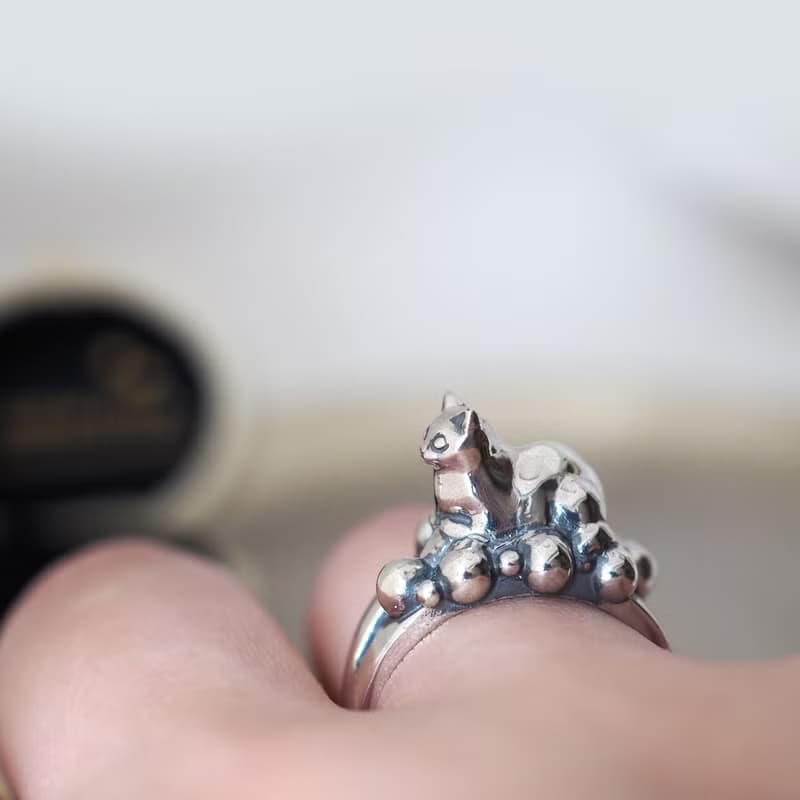 何かの上に香箱座り猫リング