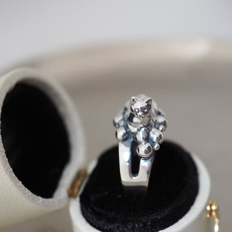 何かの上に香箱座り猫リング