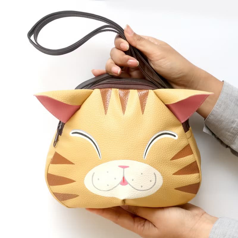 Orange cat crossbody bag is compact fro carrying mobile phones.