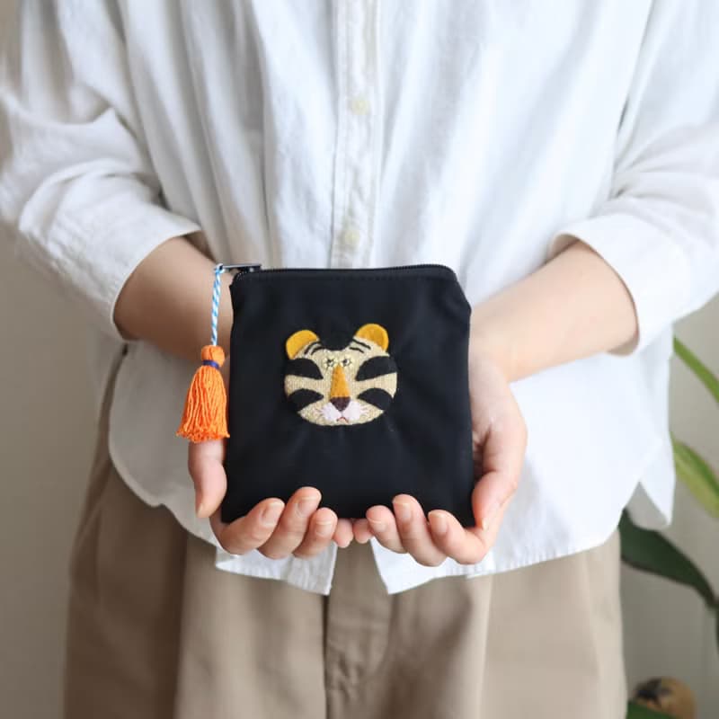 刺しゅう風アップリケ ほっこりトラの黒ポーチ カラフルタッセルつき