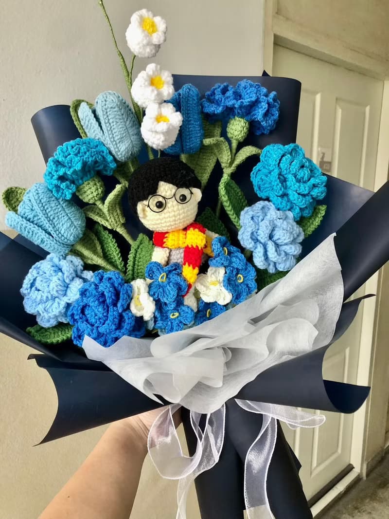 Blue-toned yarn flower bouquet with a male doll.