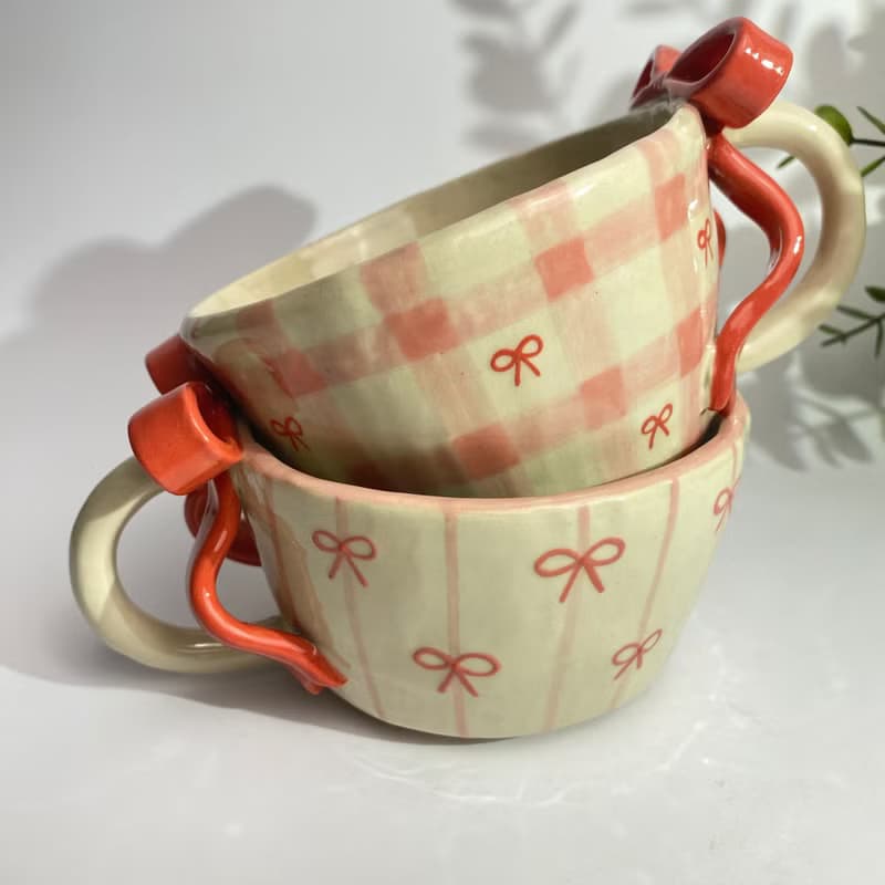 Handmade ceramic mug with a cute checkered pattern and red bow.