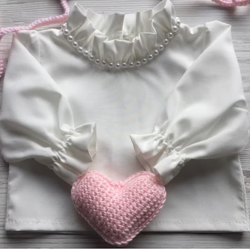 Pink knit romper, hat booties, blouse and white blanket with four pink hearts.