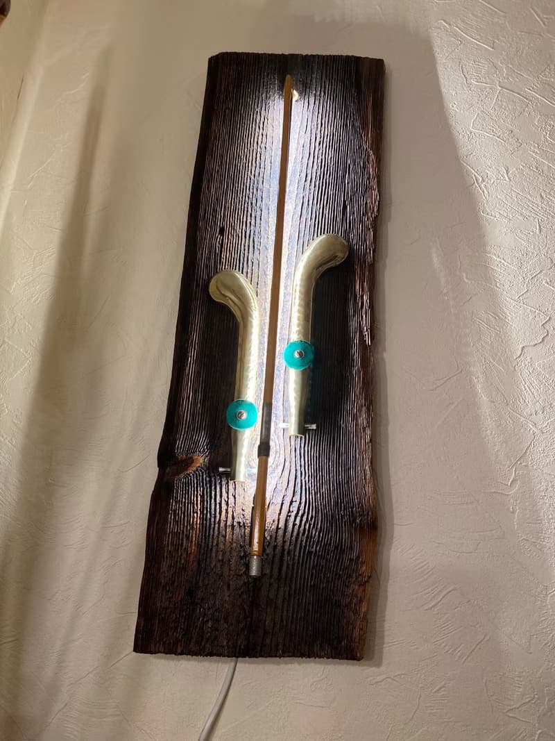 Wall sconce of antiques violin bow and brass pedals from the piano