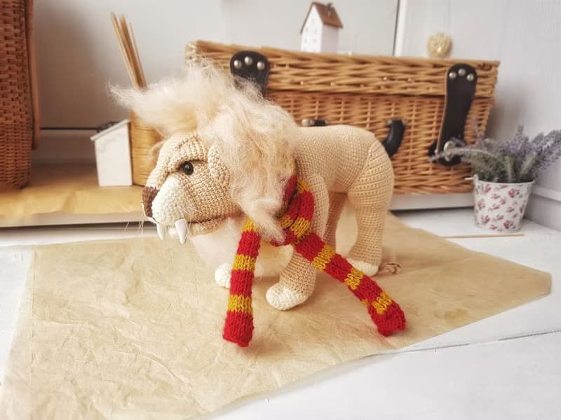 Soft toy lion in a scarf Gryffendor. Harry Potter symbol. Realistic lion figurin