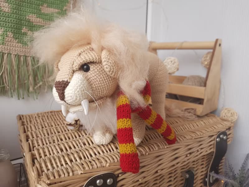 Soft toy lion in a scarf Gryffendor. Harry Potter symbol. Realistic lion figurin