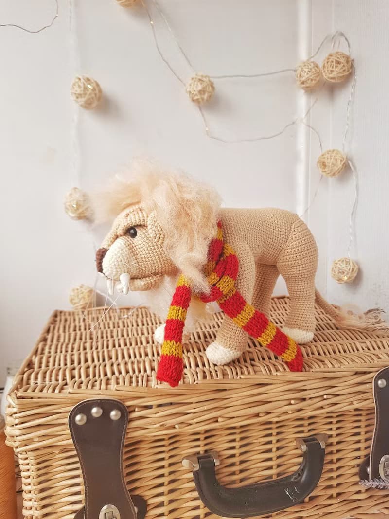 Soft toy lion in a scarf Gryffendor. Harry Potter symbol. Realistic lion figurin
