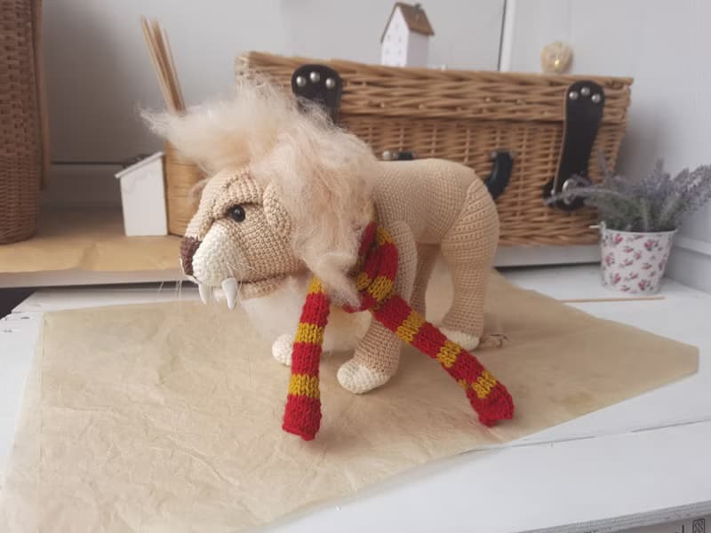 Soft toy lion in a scarf Gryffendor. Harry Potter symbol. Realistic lion figurin