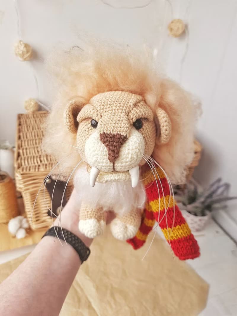 Soft toy lion in a scarf Gryffendor. Harry Potter symbol. Realistic lion figurin