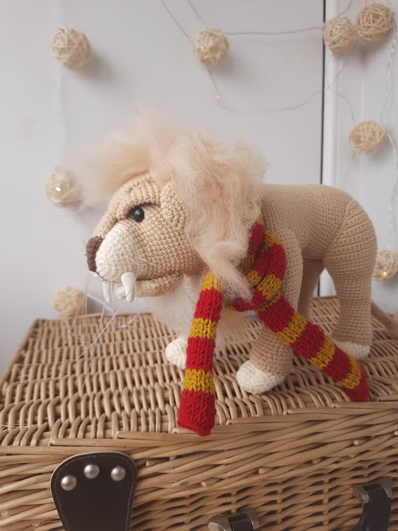 Soft toy lion in a scarf Gryffendor. Harry Potter symbol. Realistic lion figurin
