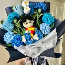 Blue-toned yarn flower bouquet with a male doll.