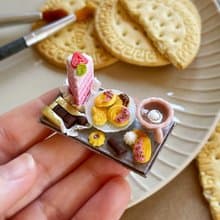 Miniature set of a piece of cake with strawberries, chocolate and a cup of tea