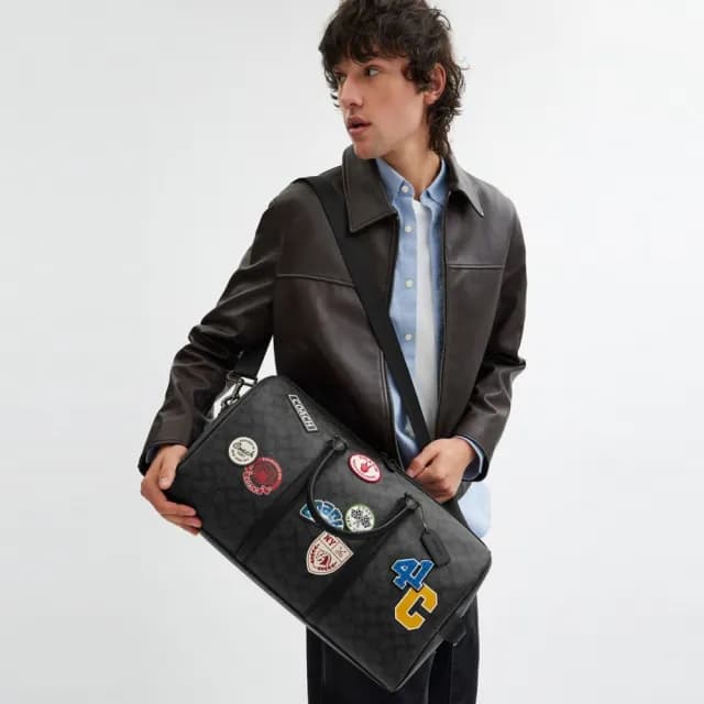 【COACH】蔻馳官方直營 VENTURER 經典 SIGNATURE 帆布與徽章旅行袋 旅行包 斜背包-炭黑色 混合色(CY829)