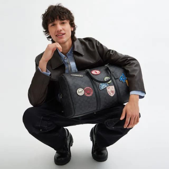 【COACH】蔻馳官方直營 VENTURER 經典 SIGNATURE 帆布與徽章旅行袋 旅行包 斜背包-炭黑色 混合色(CY829)